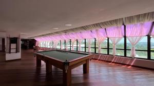 a pool table in a room with windows at Apartamento no Home Green Home - Vista para a montanha in Campos do Jordão