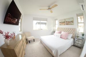 a white bedroom with a bed and a tv at New 4 Bedroom Home with Ocean and Gorgeous Mountain Views in the gated community of Mauna Olu in Waianae