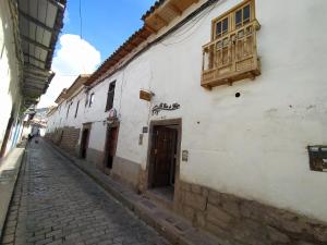 eine Gasse mit einem weißen Gebäude und einer Holztür in der Unterkunft La Casa de Mayte in Cusco