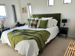 a bedroom with a large bed with a green headboard at Peppertree lodge in Havelock North
