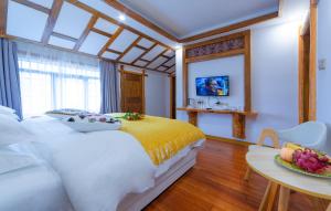 a bedroom with a white and yellow bed and a table at Easy House in Zhangjiajie