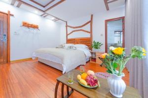 Un dormitorio con una cama y una mesa con un bol de fruta en Easy House, en Zhangjiajie