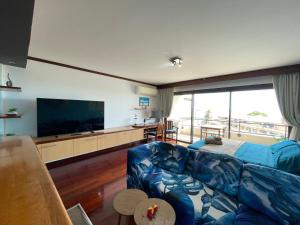 un soggiorno con divano blu e TV a schermo piatto di Blue Moana Studio Papeete - Sea View, AC, Fast Wifi, Pool, Gym a Papeete
