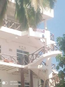 een wit gebouw met palmbomen ervoor bij Kassandra Beach Hotel in Nungwi