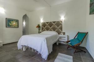 a bedroom with a white bed and a chair at Ecosoul Bugambilia villa in Puerto Vallarta