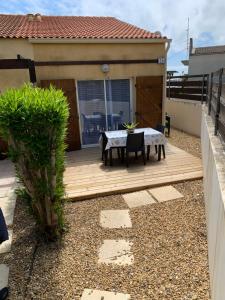 un patio con mesa y sillas en una terraza de madera en Pavillons 7 et 56 Narbonne Plage, en Narbonne-Plage