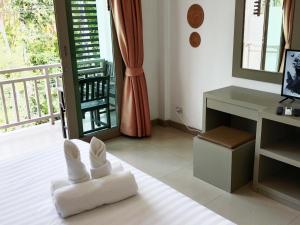 Cette chambre comprend une chaise blanche, un bureau et un balcon. dans l'établissement Ampha Place Hotel, à Mae Nam Beach