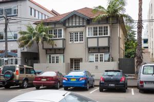 eine Gruppe von Autos, die auf einem Parkplatz vor einem Haus geparkt sind in der Unterkunft Chic Apartment with Sun Lounge Near Manly Beach in Sydney