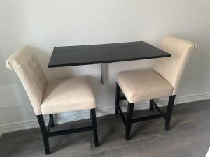 una mesa negra y dos sillas blancas junto a una mesa y sillas en Keppel Circle Residence en Brampton