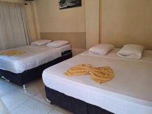 two beds with towels on them in a room at Hotel Italyan's in Ponta Porã