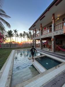 a man standing in a swimming pool next to a building at Tabularasa - T Luxury Boutique in New Agutaya