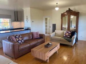 Una sala de estar con un sofá y una mesa de café. en IRONBARK FARM Farmhouse on 52 acres in the scenic Yarra Valley, en Glenburn