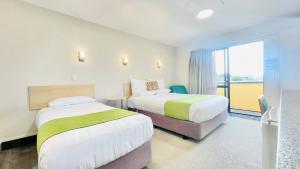 ein Hotelzimmer mit 2 Betten und einem Fenster in der Unterkunft Bella Vista Motel Whangarei in Whangarei
