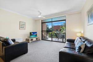 a living room with two leather couches and a balcony at Hawaiian Gardens 22 in Coffs Harbour