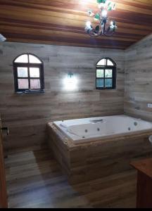 ラゴイーニャにあるAconchegante Sítio em Lagoinha SPの大きなバスタブ、窓2つが備わる客室です。