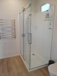a bathroom with a glass shower with a toilet at Purangi Beachhouse - 2 Bedroom in Cooks Beach