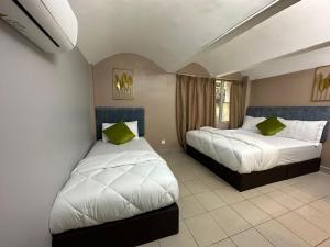 1 dormitorio con 2 camas y almohadas verdes en SS Grey Hotel en Kuala Lumpur