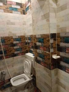 a bathroom with a toilet and a tiled wall at Varanasi homestay in Varanasi
