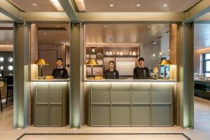 Atour Hotel Shanghai World Expo West Gaoke Road في شانغهاي: مجموعة من اربع رجال تقف عند كونتر في مطعم