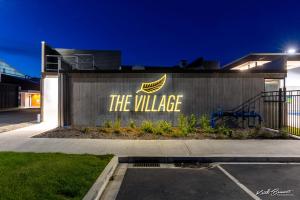 a building with a sign that reads the village at Village Apartments at NZCIS in Upper Hutt