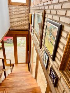 a hallway with paintings on a brick wall at Cabana Charme Guará- 500 metros do centro in Guaramiranga