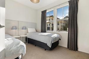 a bedroom with two beds and a window at Fletcher Cottage in Arrowtown