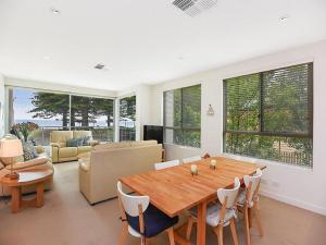 uma sala de estar com uma mesa de madeira e cadeiras em Breeze Beachfront Apartment em Victor Harbor