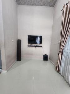 uma sala de estar com uma televisão de ecrã plano na parede em HomeStay Pandan Baru em Halangan