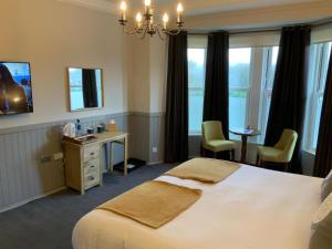 Habitación de hotel con cama, escritorio y ventanas en The Sun Inn en Windermere