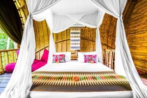 una camera con letto a baldacchino e cuscini rosa di Swarma Villa Ubud Near Sacred Monkey Forest Sanctuary ad Ubud