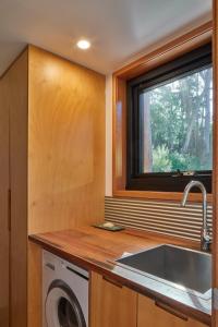 a kitchen with a sink and a washing machine at The Lookout House at Pirates Bay in Eaglehawk Neck