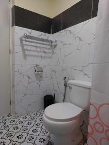 La salle de bains est pourvue de toilettes blanches et d'un mur en marbre. dans l'établissement T&J Guest House, 