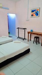 a room with two beds and a wooden table at Kuantan Town House in Kuantan