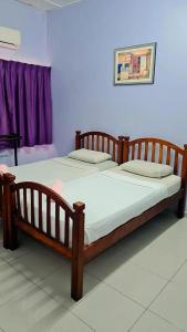 a large wooden bed in a bedroom with a purple wall at Kuantan Town House in Kuantan