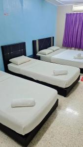a group of four beds in a room at Kuantan Town House in Kuantan