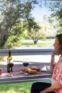 a woman sitting at a table with two glasses of wine at Robe Holiday Park in Robe