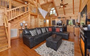 a living room with a black leather couch in a cabin at A Wildflower Retreat in Gatlinburg