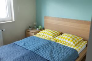 a bedroom with a blue bed with yellow and white pillows at Apartament Kościuszki Chorzów in Chorzów