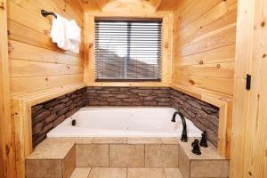 a bath tub in a wooden bathroom with a window at Swept Away in Gatlinburg