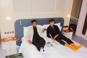 バンコクにあるザ スタンダード バンコク マハナコーンのホテルルームのベッドに座って2人の男性