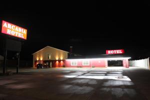 a neon hotel sign in a parking lot at night at Arcadia Hotel in Gering