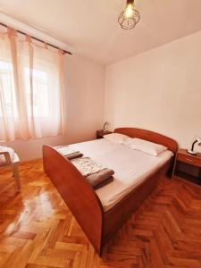a bedroom with a large bed with a wooden floor at Apartments Mira - 20 m from pebble beach in Zaboric