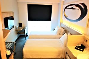 a hotel room with two beds and a desk at Enso Hotel in Cikarang
