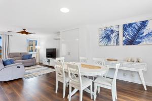 una sala de estar blanca con mesa y sillas en Nautica Residences Hillarys, en Perth