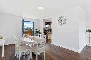 uma sala de jantar com mesa e cadeiras e um relógio em Nautica Residences Hillarys em Perth