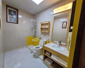 uma casa de banho com um lavatório, um WC e um espelho. em Camphor Hotel em Ras al-Khaimah