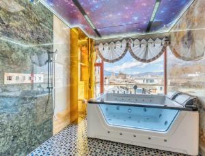 Lijiang Shuhe Zuo'an Inn في ليجيانغ: حوض استحمام في حمام ذو سقف نجمة