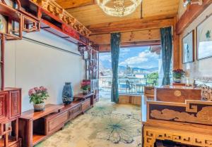 uma sala de estar com uma grande televisão e uma grande janela em Lijiang Shuhe Zuo'an Inn em Lijiang