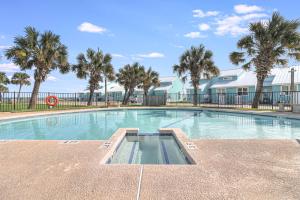 a swimming pool with palm trees in front of a building at Bayfront Kontiki in Rockport