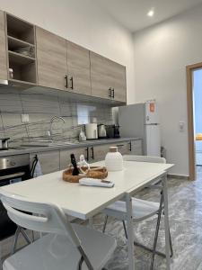 a kitchen with a white table and white chairs at Pefki apartments in Limenaria